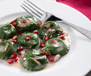 Green ravioli filled with cod, pomegranate, and almonds