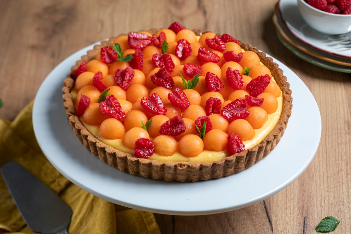Tart with cream, melon, and raspberries