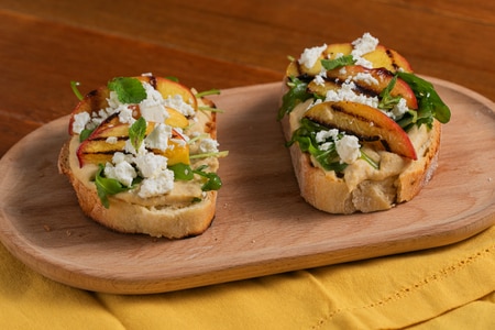 Crostini with hummus, grilled peaches, feta, and arugula