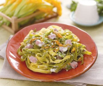 Paglia and fieno with ricotta cream, zucchini flowers and diced ham