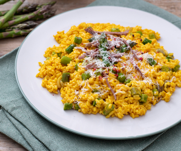 Yellow risotto with shredded meat, asparagus, and Grana Padano PDO