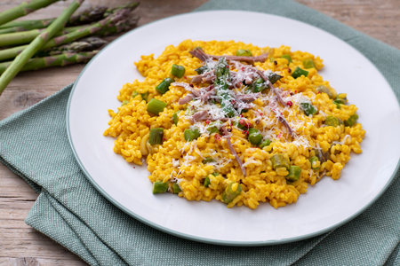 Yellow risotto with shredded meat, asparagus, and Grana Padano PDO