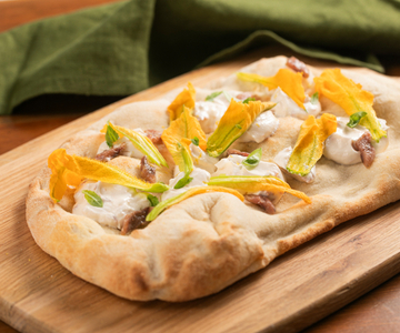 Pinsa with zucchini flowers, anchovies and cheese cream